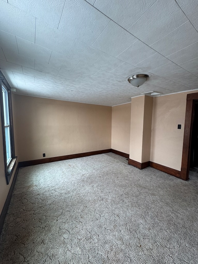 carpeted empty room featuring a textured ceiling and baseboards