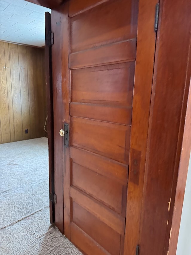 interior details with carpet flooring and wood walls