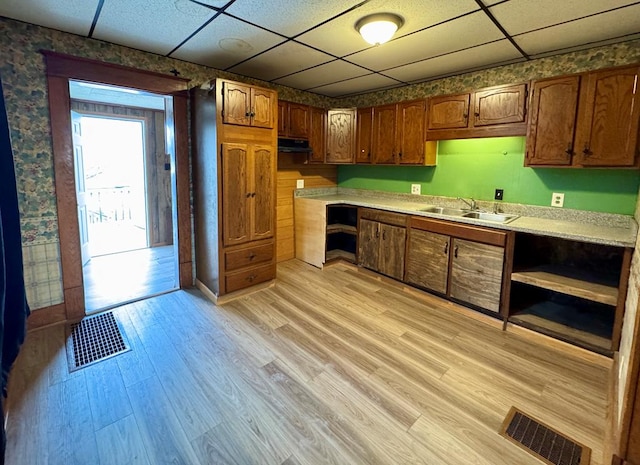 kitchen with light countertops, light wood finished floors, a sink, and visible vents