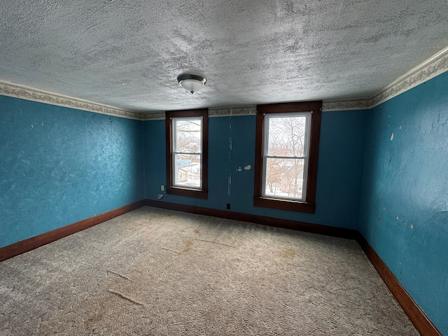 carpeted spare room featuring a textured wall, a textured ceiling, and baseboards