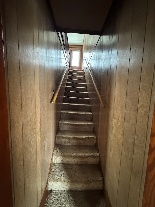 staircase featuring wood walls