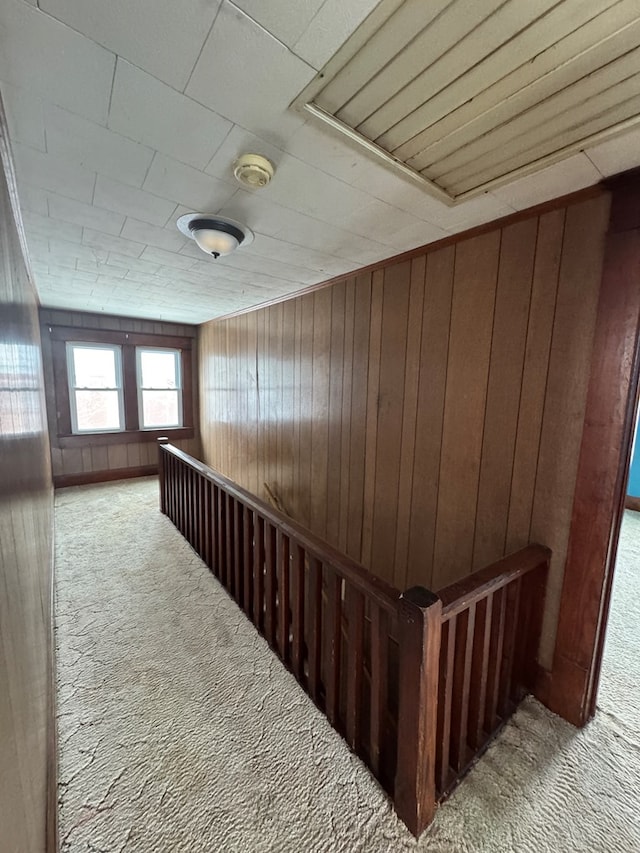 hall with carpet flooring and wooden walls