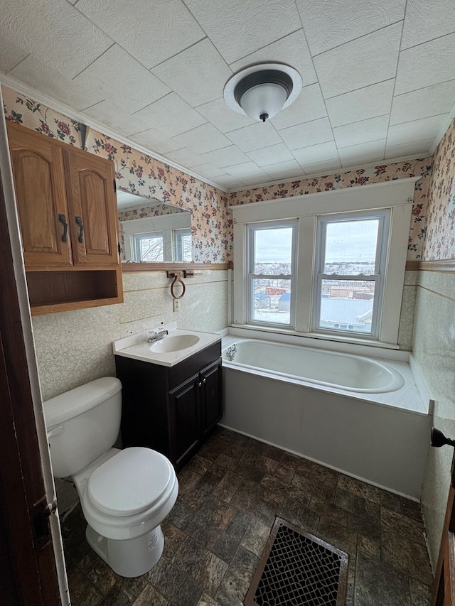 full bath featuring a garden tub, toilet, wainscoting, vanity, and wallpapered walls