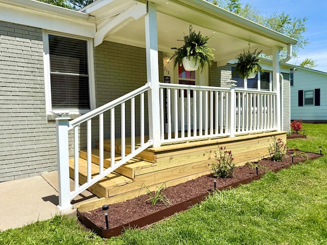 713 E Dear St, Kirksville, MO 63501 - view of exterior entry featuring brick siding, covered porch, and a yard