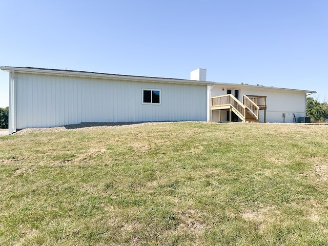 rear view of house with central AC and a lawn