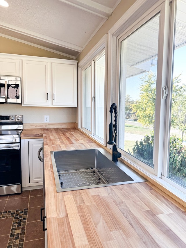 kitchen with white cabinetry, sink, wood counters, lofted ceiling, and appliances with stainless steel finishes