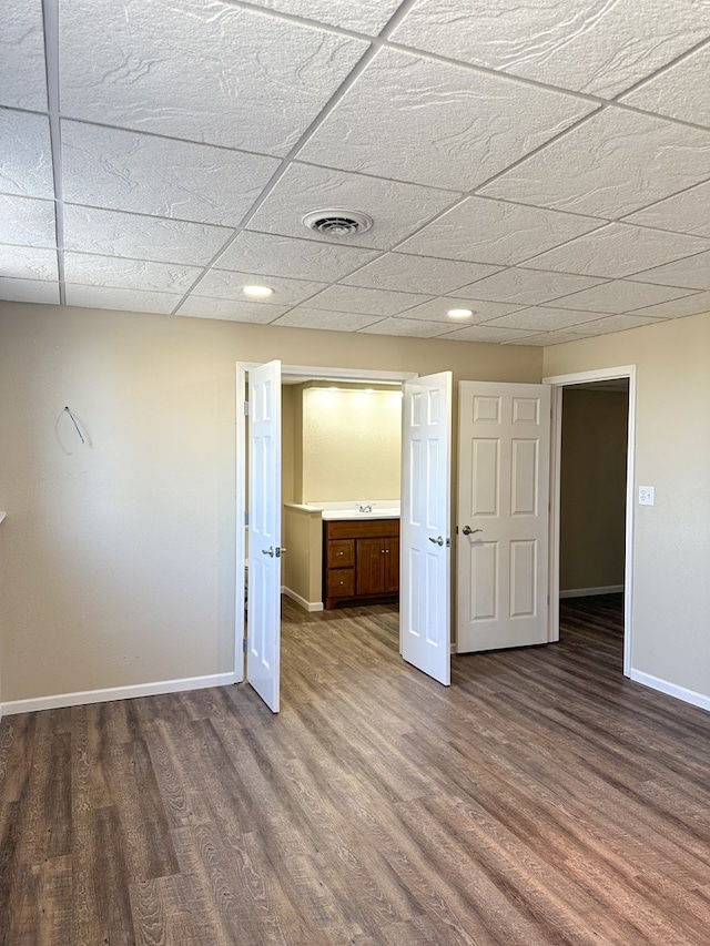 unfurnished bedroom with a drop ceiling, hardwood / wood-style floors, and sink