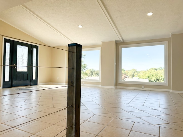 entrance foyer with light tile patterned floors, a textured ceiling, and vaulted ceiling