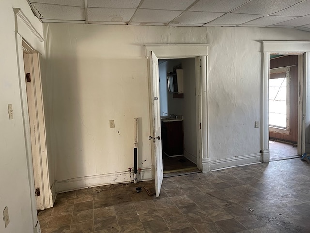 empty room with a drop ceiling and baseboards