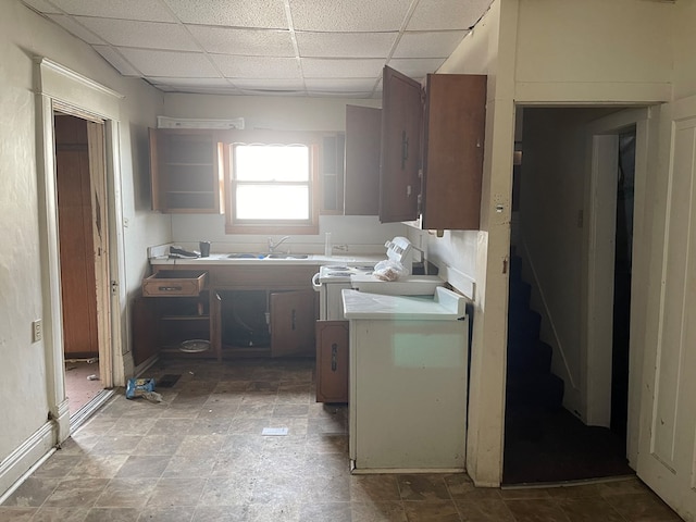 kitchen featuring tile countertops, a drop ceiling, and a sink