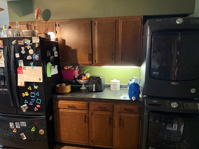 2515 N E St, Kirksville, MO 63501 - kitchen featuring black fridge with ice dispenser, stacked washer and clothes dryer, dark countertops, and brown cabinets