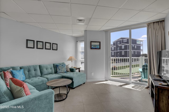 tiled living area featuring baseboards, a paneled ceiling, and visible vents