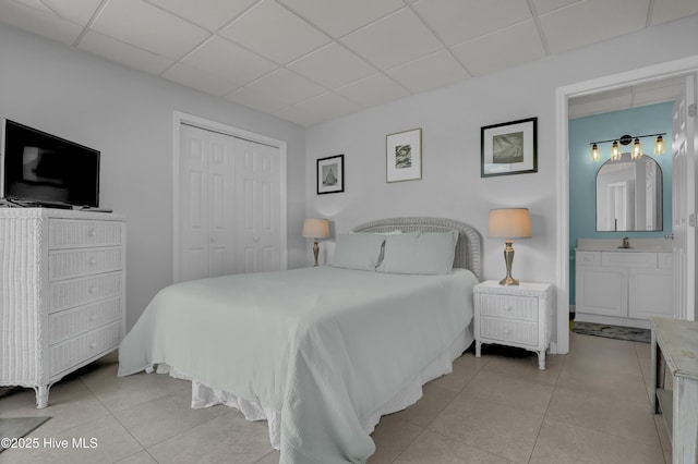 bedroom featuring a closet, a drop ceiling, and light tile patterned flooring