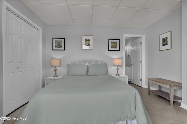tiled bedroom with a closet, baseboards, and a drop ceiling