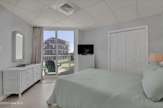 bedroom featuring access to exterior, visible vents, light tile patterned floors, a closet, and a drop ceiling