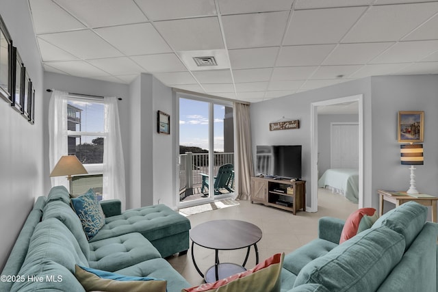 living room with visible vents, light tile patterned floors, and a drop ceiling
