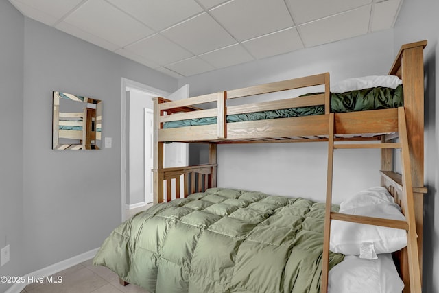 bedroom featuring tile patterned flooring, a paneled ceiling, and baseboards