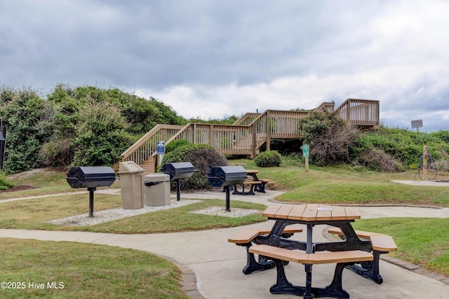 view of property's community with a yard, a patio, a wooden deck, and stairs