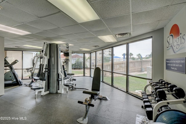 workout area with expansive windows, a paneled ceiling, and visible vents
