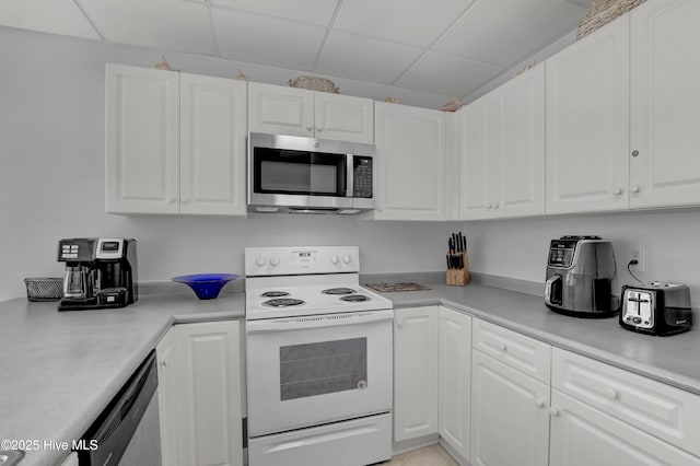 kitchen with light countertops, appliances with stainless steel finishes, a drop ceiling, and white cabinets