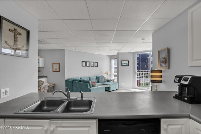 kitchen with a sink, a drop ceiling, white cabinetry, and dishwasher