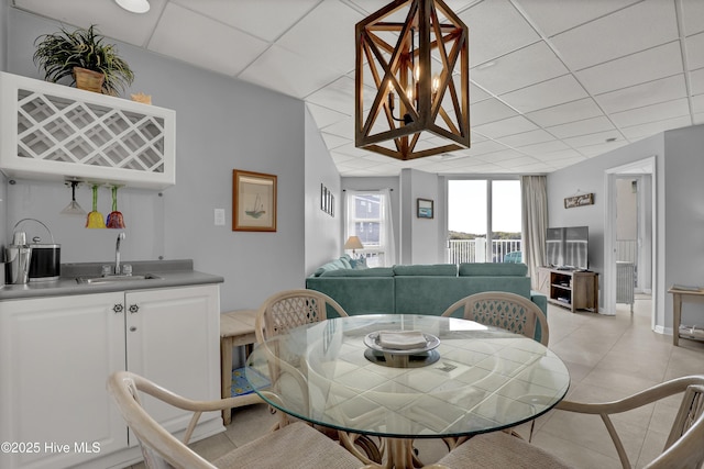 dining space with indoor wet bar, a drop ceiling, and light tile patterned floors