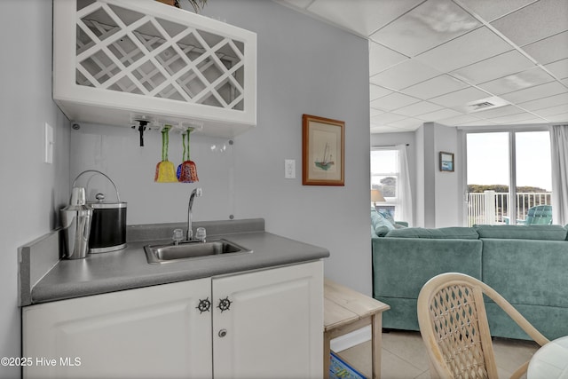 bar with indoor wet bar, a sink, light tile patterned floors, and visible vents