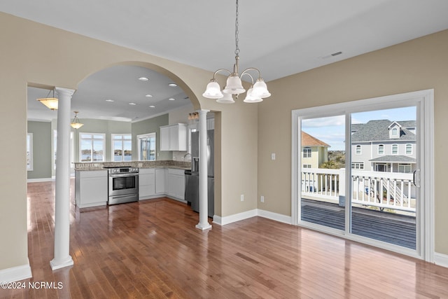 kitchen featuring appliances with stainless steel finishes, white cabinetry, a healthy amount of sunlight, hardwood / wood-style floors, and pendant lighting