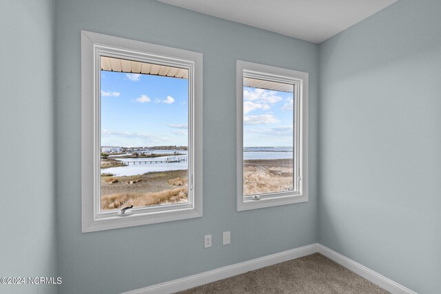 carpeted empty room featuring plenty of natural light and a water view