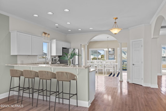 kitchen featuring light stone counters, white cabinetry, stainless steel fridge, dark hardwood / wood-style floors, and pendant lighting