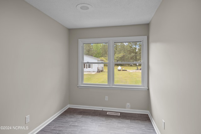 unfurnished room with hardwood / wood-style flooring and a textured ceiling