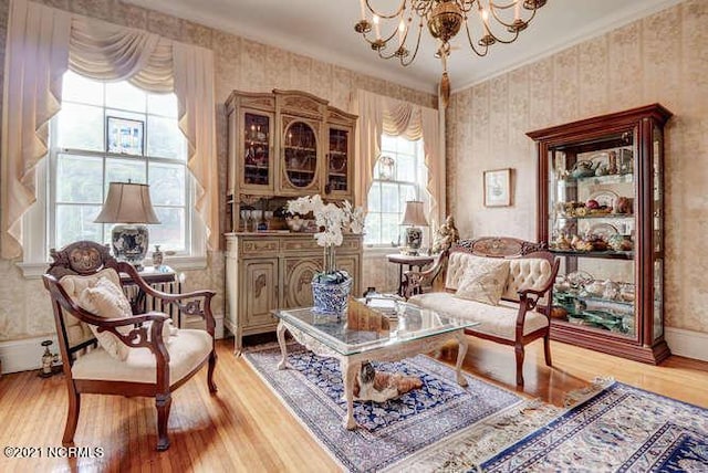 sitting room with ornamental molding, light hardwood / wood-style floors, and a notable chandelier