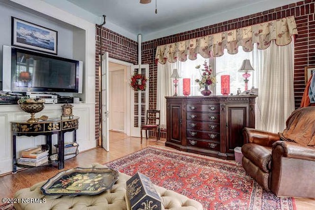 living room with brick wall and light hardwood / wood-style floors
