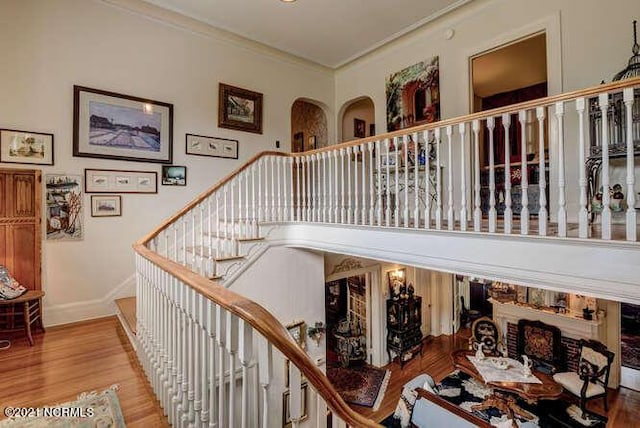 staircase with ornamental molding and light wood-type flooring