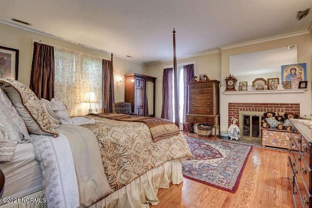 bedroom with a fireplace, ornamental molding, and hardwood / wood-style flooring