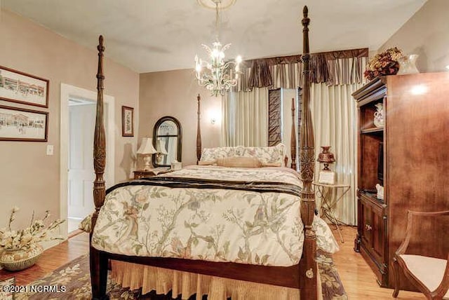 bedroom with an inviting chandelier and light hardwood / wood-style floors