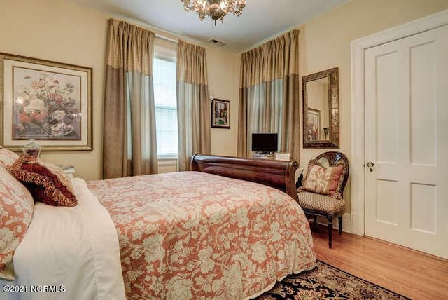 bedroom with hardwood / wood-style floors and a chandelier