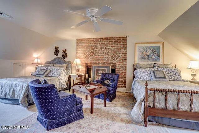 carpeted bedroom with ceiling fan, lofted ceiling, brick wall, and a brick fireplace