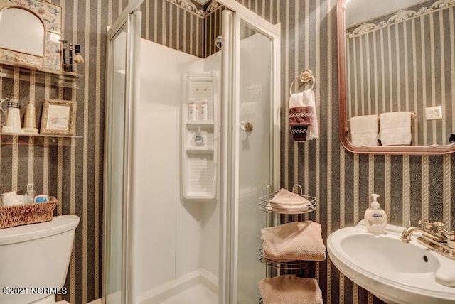 bathroom with sink, toilet, and a shower with shower door