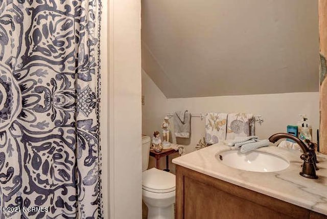 bathroom featuring lofted ceiling, toilet, and vanity