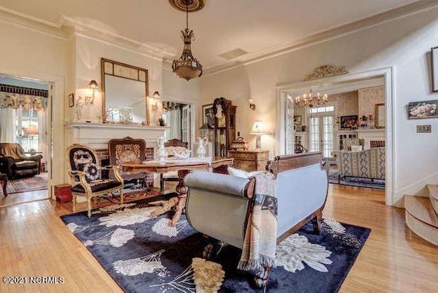 living room with crown molding, light hardwood / wood-style floors, and an inviting chandelier