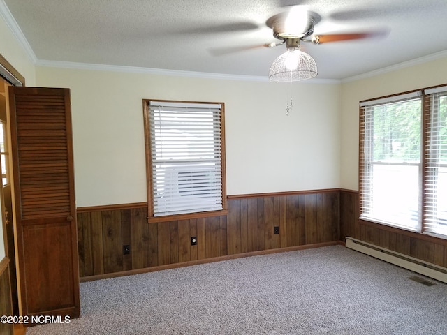 spare room featuring ornamental molding, light colored carpet, ceiling fan, and baseboard heating