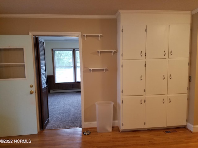 interior space featuring ornamental molding, light wood-type flooring, and baseboard heating