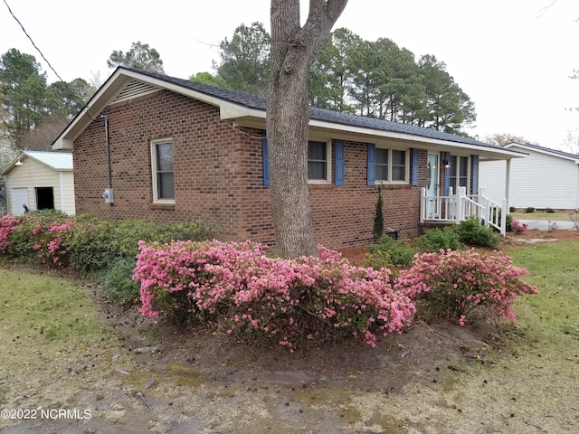 view of side of property with covered porch and a lawn