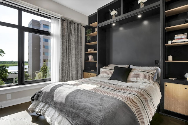 bedroom featuring baseboards, multiple windows, and wood finished floors