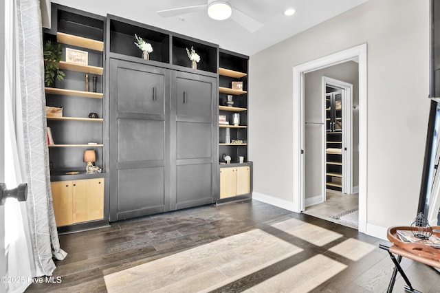 interior space with built in features, baseboards, a ceiling fan, and dark wood-style flooring