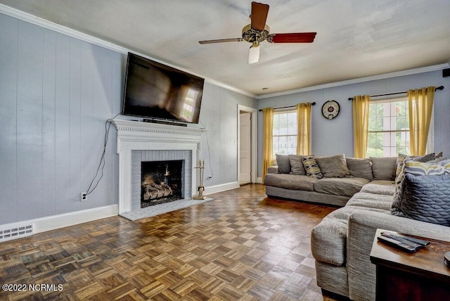 living room with dark parquet floors, ornamental molding, a fireplace, and ceiling fan