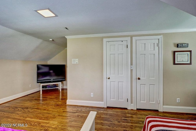 bedroom featuring a textured ceiling, crown molding, dark wood-type flooring, and vaulted ceiling