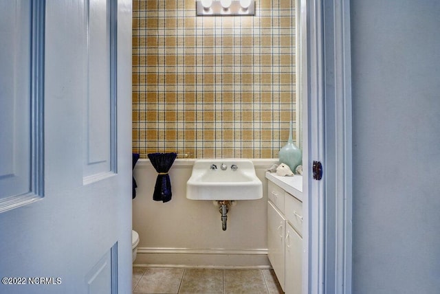 bathroom with toilet, tile floors, and sink