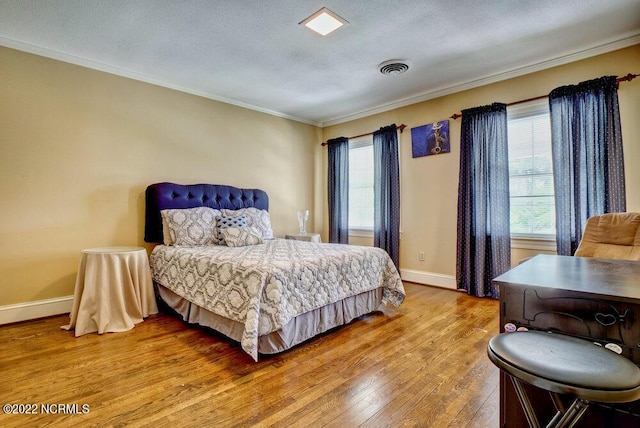 bedroom featuring ornamental molding, light hardwood / wood-style floors, and a textured ceiling